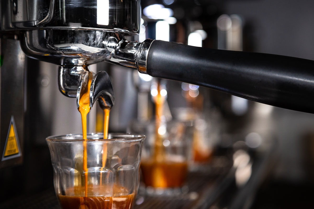 Close-up view of golden espresso liquid pouring into shot glasses.