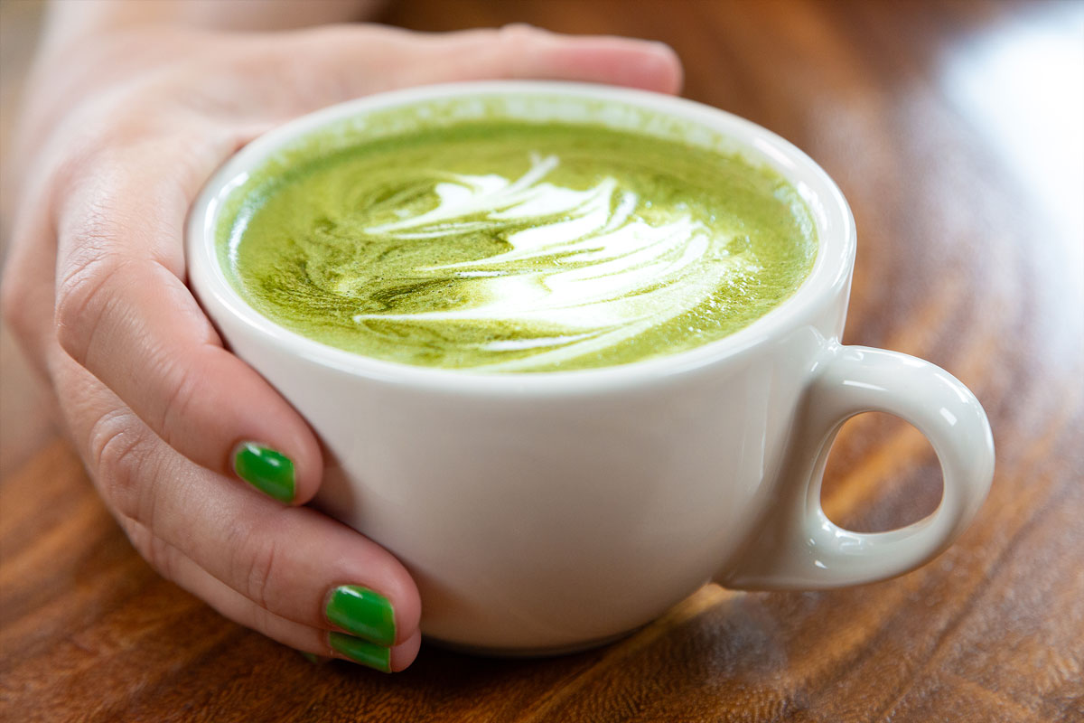 A person holding a cup of green tea latte at a local café.