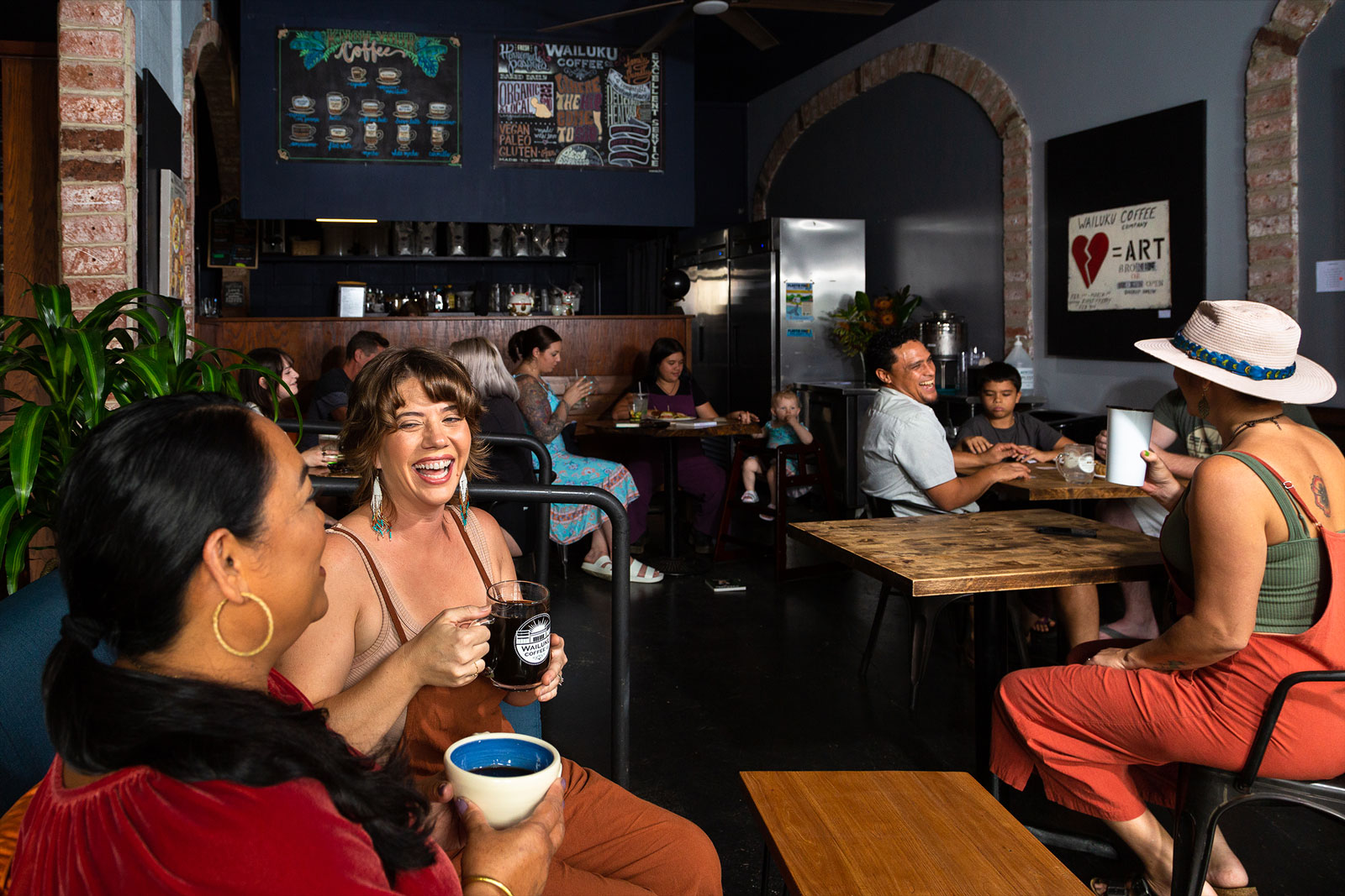 People come together and socialize around tables at a Wailuku Coffee Company Maui café.