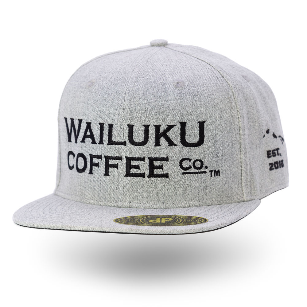 The grey snapback hat features a front view of the Wailuku Coffee Co logo embroidered in black.