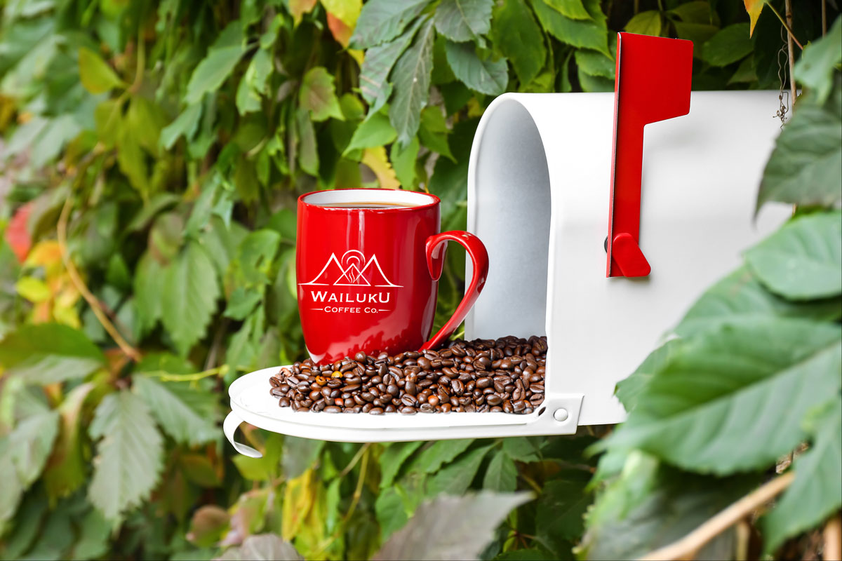 Coffee subscriptions show a red cup of coffee with a white Wailuku Coffee Co. logo sitting on the door of an open mailbox with roasted coffee beans.